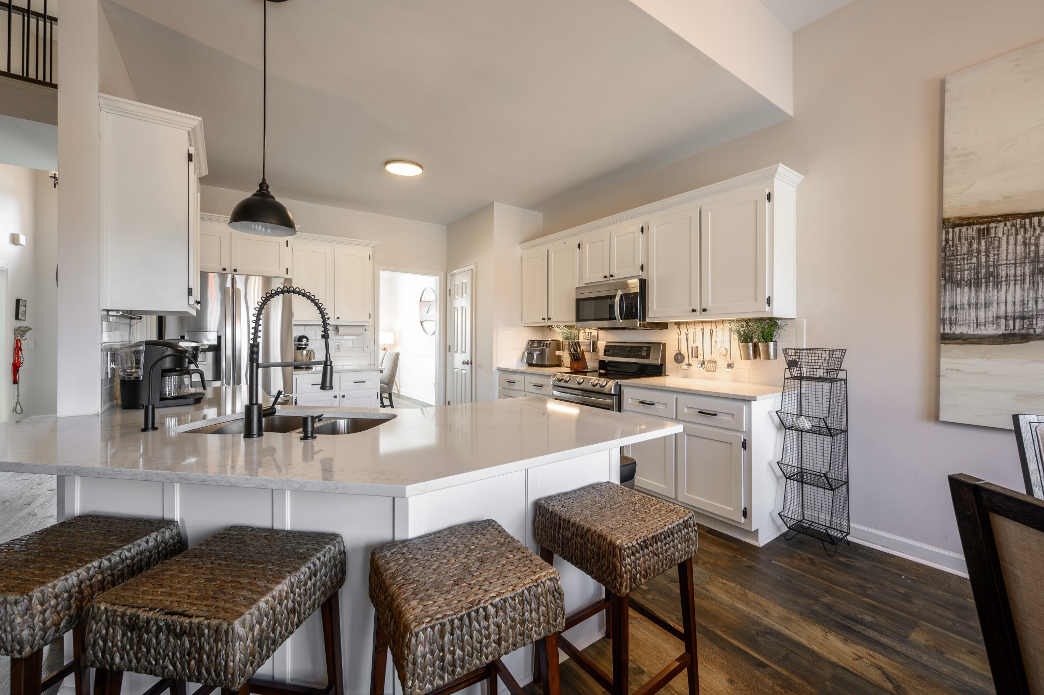 Bright white kitchen with quartz island and woven barstools